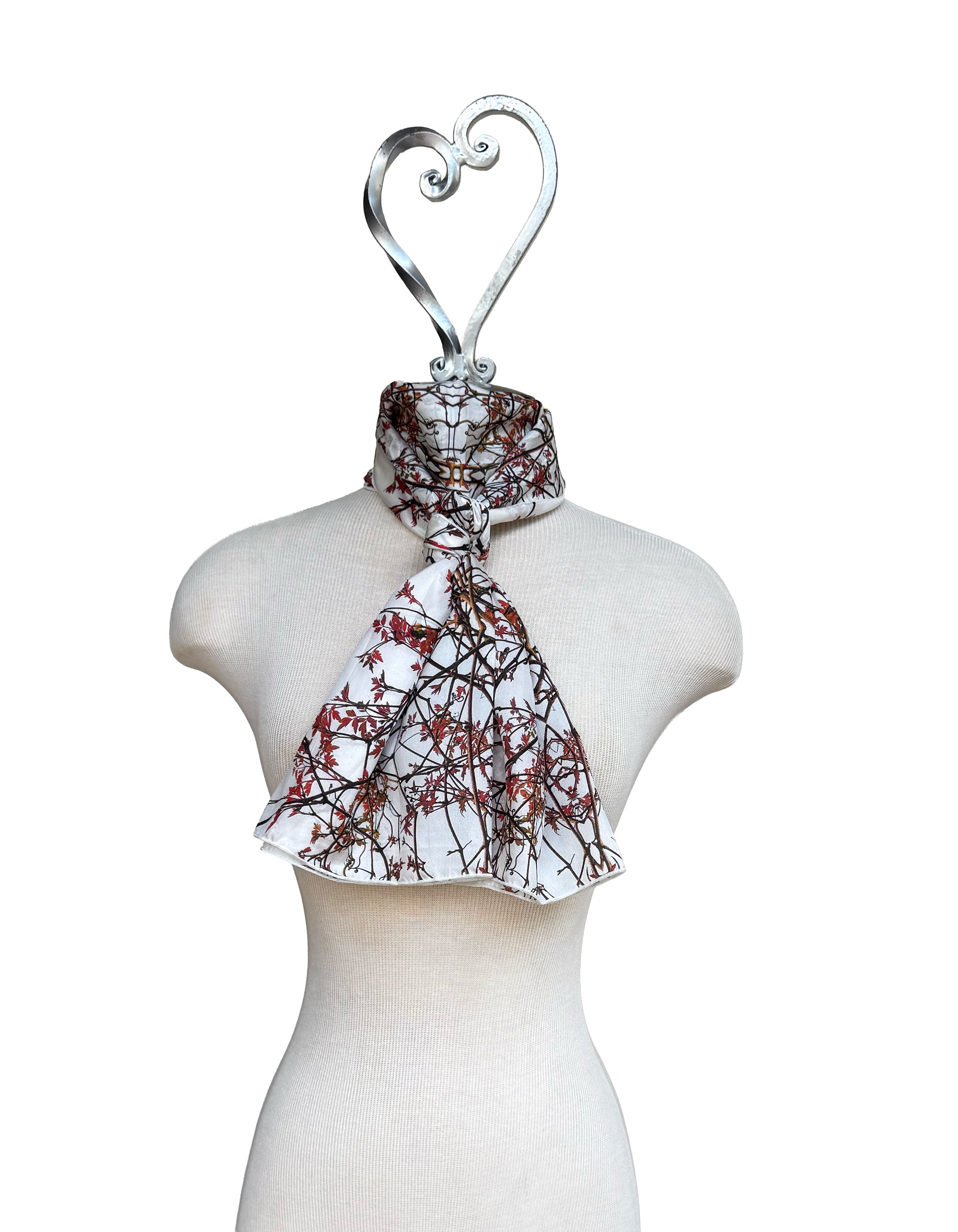 Mannequin wearing a patterned scarf with a heart-shaped hanger on a white background