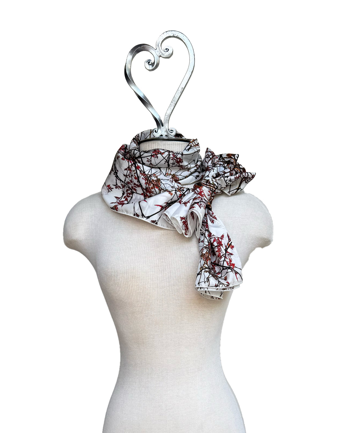 Mannequin wearing a floral-patterned scarf with a decorative heart-shaped hanger on a white background